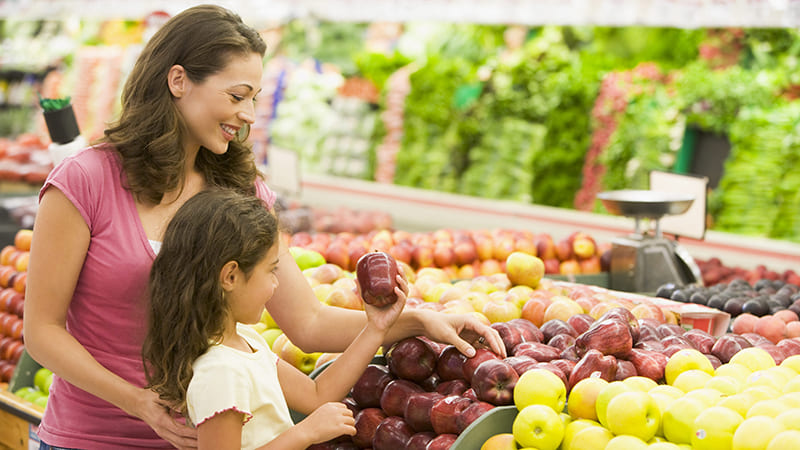Выбирать фрукты и овощи в магазине