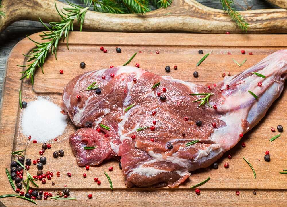 Мясо оленя с солью и перцем на разделочной доске